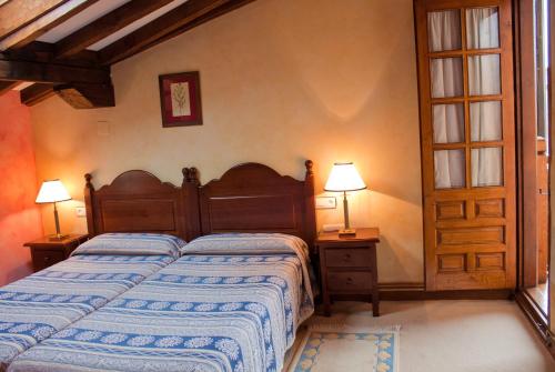 um quarto com uma cama, 2 candeeiros e uma porta em La Casa del Organista em Santillana del Mar