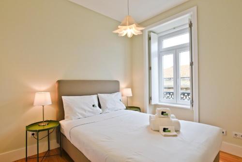 een slaapkamer met een groot wit bed en een raam bij BmyGuest - Arroios Cosy Apartment in Lissabon