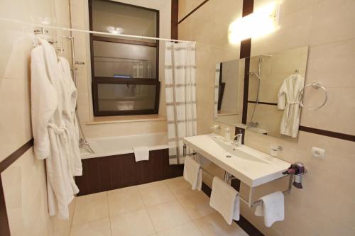a white bathroom with a sink and a mirror at Ekaterina II Hotel in Odesa
