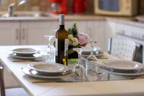 a table with plates and a bottle of wine and flowers at Tesori Dassia Villas in Dassia
