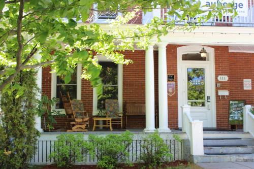 a brick house with two chairs on the front porch at Auberge de Jeunesse Magog-Orford Hostel in Magog-Orford