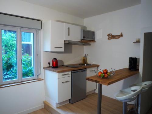 una cucina con mobili bianchi, un tavolo e una finestra di Studio moderne, hypercentre de Cholet, arrivée autonome ! a Cholet