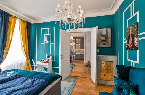 プラハにあるGlamour Frida apartmentの青い壁のベッドルーム1室、シャンデリアが備わります。