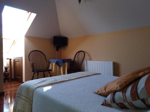 a bedroom with a bed and two chairs and a table at Casa de Labranza A Rega in Combarro