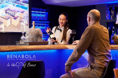 a woman sitting at a bar talking to a man at Benabola Hotel & Suites in Marbella