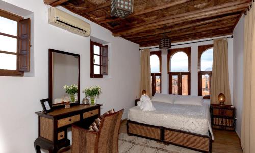 a bedroom with a bed and a desk and windows at Dar Mo'Da in Marrakesh