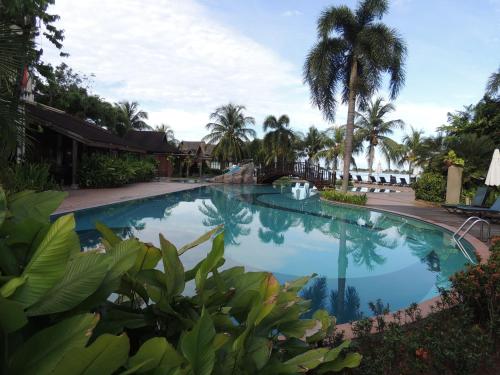 a large swimming pool with palm trees in a yard at Langkawi Lagoon Resort Water Chalet in Pantai Cenang