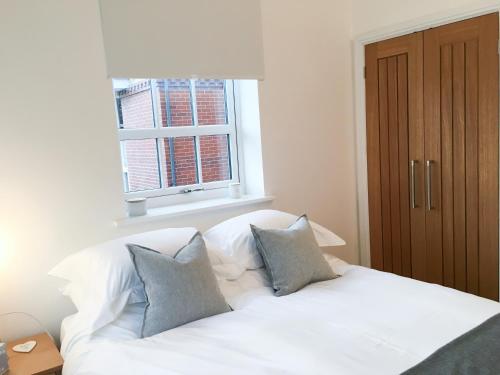 a white bed with pillows in a room with a window at No 3 Old Printworks in Winchester