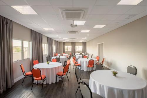 a conference room with white tables and red chairs at Intercity Ribeirão Preto in Ribeirão Preto