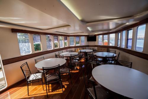 a dining room with tables and chairs and windows at Tapri - Hotel Flutuante in Barra Bonita