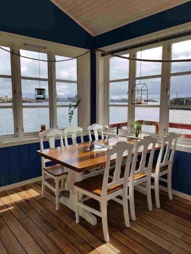 a dining room with a wooden table and white chairs at Å Rorbuer - by Classic Norway Hotels in Å