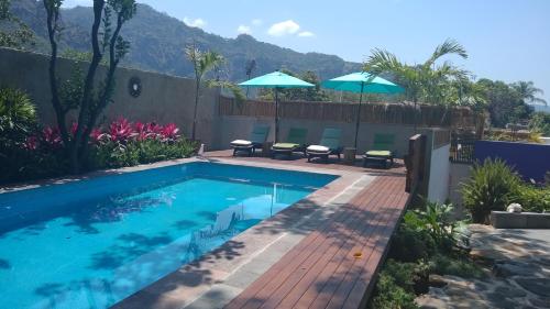 einen Pool mit Stühlen und Sonnenschirmen im Hof in der Unterkunft Sierra Central By Chic Hotel Group in Tepoztlán