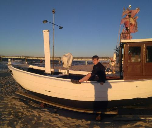 a young boy sitting on a boat on the beach at Koserow Ferienwohnung Fam. Jäger 400m zum Strand in Ostseebad Koserow