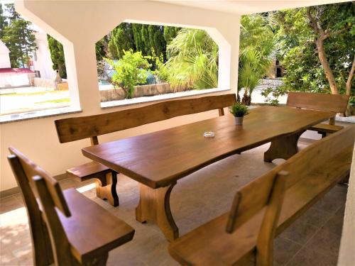 una mesa de madera y bancos en una habitación con ventana en Villa Gaj, en Novalja