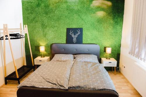 a bedroom with a bed with a green wall at Nexus Apartmenthotel in Hévíz