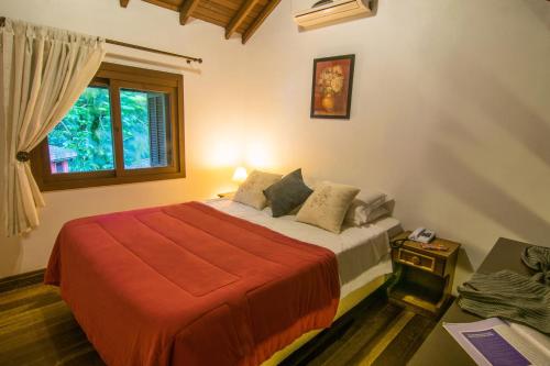 um quarto com uma cama com um cobertor vermelho e uma janela em Pousada Rosa em Gramado