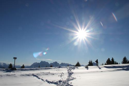 a snow covered field with the sun in the sky at Landhof in Monguelfo