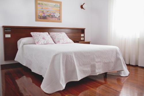 Schlafzimmer mit einem Bett mit weißer Bettwäsche und rosa Kissen in der Unterkunft Hotel Victorino in Silleda