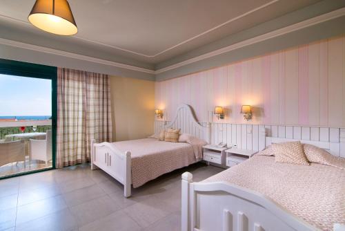 a bedroom with two beds and a balcony at Ocean Beach Hotel in Skala Potamias
