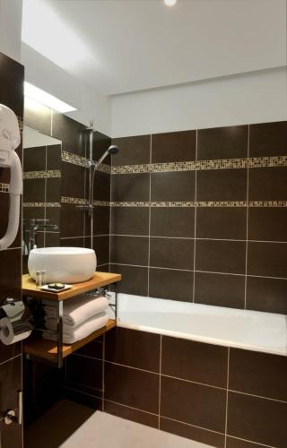 une salle de bain avec une baignoire et un lavabo dans l'établissement Hôtel Volney Opéra, à Paris