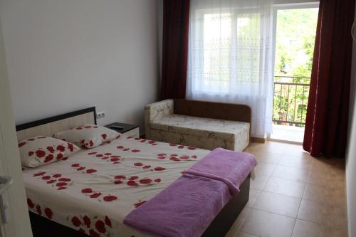 a bedroom with a bed and a chair and a window at Guest House U Aleny in Gagra