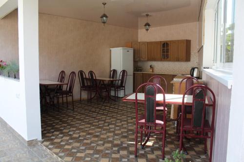 a kitchen with tables and chairs and a refrigerator at Guest House U Aleny in Gagra