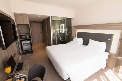 a bedroom with a large white bed and a chair at Novotel São Paulo Berrini in Sao Paulo