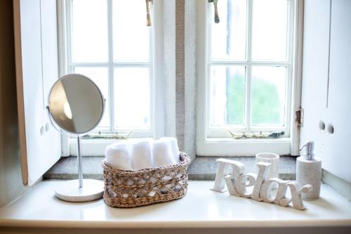 a bathroom counter with a mirror and a basket of towels at Coachmans Cottage in Stoney Middleton