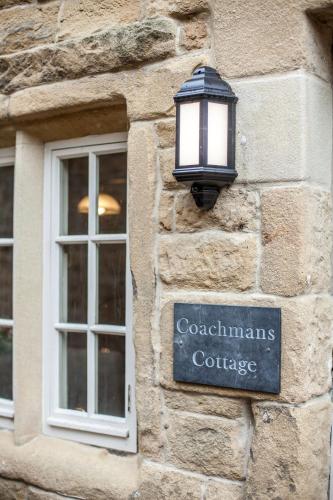 a light on the side of a stone building with a window at Coachmans Cottage in Stony Middleton