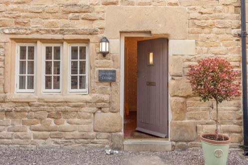 a stone building with a door and a potted plant at Coachmans Cottage in Stony Middleton