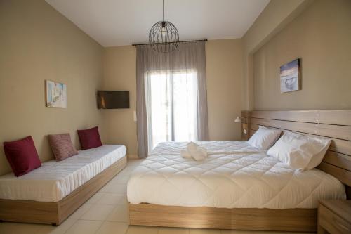 a bedroom with a large white bed and a window at Ilaeira rooms in Argasi