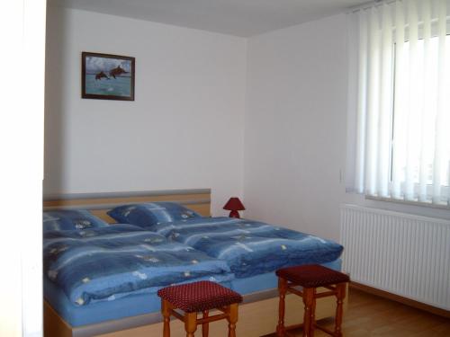 a bedroom with a blue bed with two chairs at Ferienhäuschen in Born