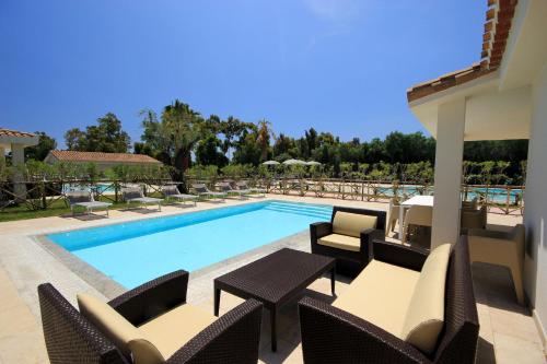 a swimming pool with chairs and a table and a table and chairs at Ville D'Ogliastra in Cardedu