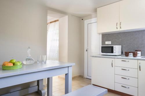 a kitchen with white cabinets and a bowl of fruit on a counter at Sandy & Sofia in Katelios
