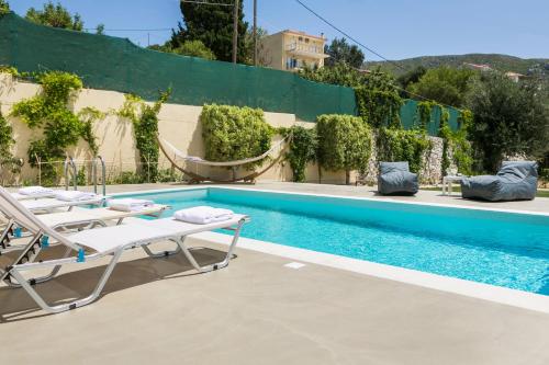 a swimming pool with two lounge chairs next to a building at Sandy & Sofia in Katelios