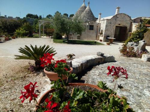 um jardim com flores vermelhas e um edifício em Trulli La collinetta em Martina Franca