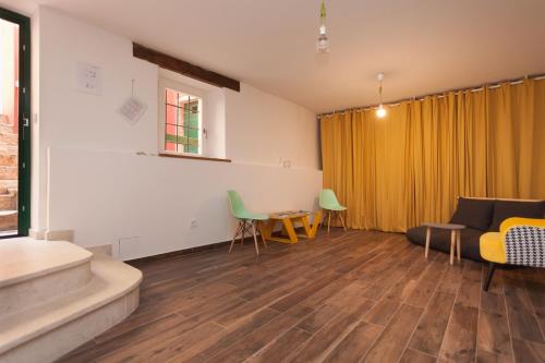 a living room with a yellow curtain and chairs at Apartments and Rooms Hey Rovinj in Rovinj
