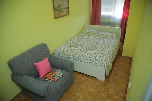 una camera con letto e sedia con cuscino rosa di Apartment Duluta a Belgrado