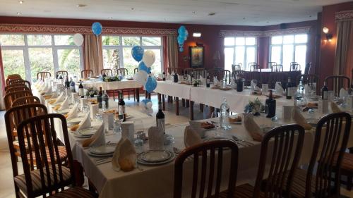 a long table with white tables and chairs in a room at Hotel Azpiazu in Muros de Nalón