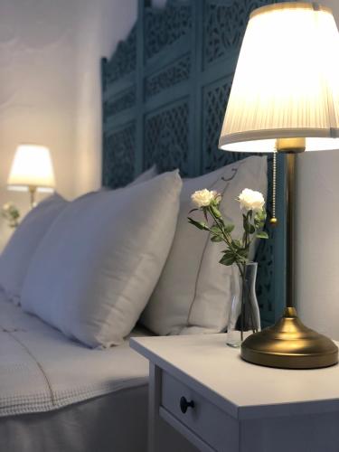 a bed with a table with a lamp and flowers on it at Jakamar Alacati in Alacati