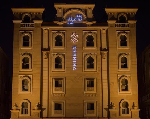 a building lit up at night with a sign on it at نورمينا الشرق للشقق المخدومة in Dammam
