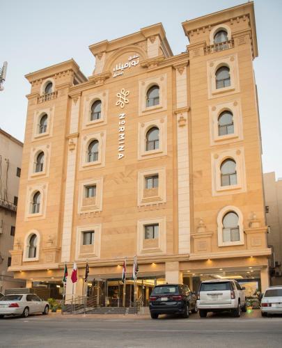 a large building with cars parked in front of it at نورمينا الشرق للشقق المخدومة in Dammam