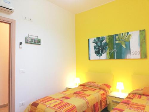 two beds in a room with yellow walls at Capo d'Orlando Apartments in Capo dʼOrlando