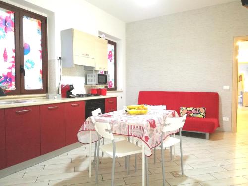 a kitchen and dining room with a table and a red couch at Capo d'Orlando Apartments in Capo dʼOrlando
