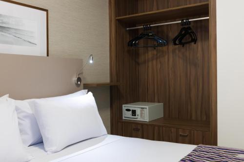 a bedroom with a bed with a clock on the wall at Matiz Multi Suites in Duque de Caxias