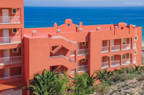 um edifício laranja com o oceano ao fundo em Residence Playa Paraiso With Ocean View em Costa Calma