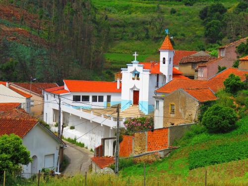 a large white church with orange roofs on a hill at Casa Eira do Povo 1 in Vale de Colmeias