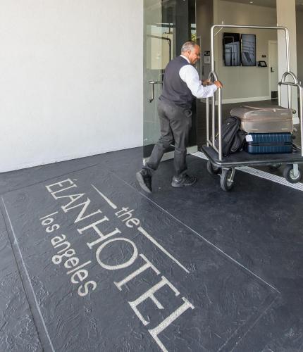 a man pushing a luggage cart in a room at Elan Hotel in Los Angeles