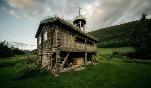 an old wooden house in a field with a tower at Kvaale Gard in Lom