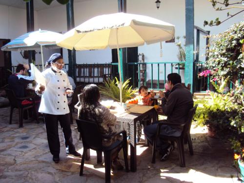 a group of people sitting at a table with an umbrella at Hotel Hacienda El Aserrio in Iza